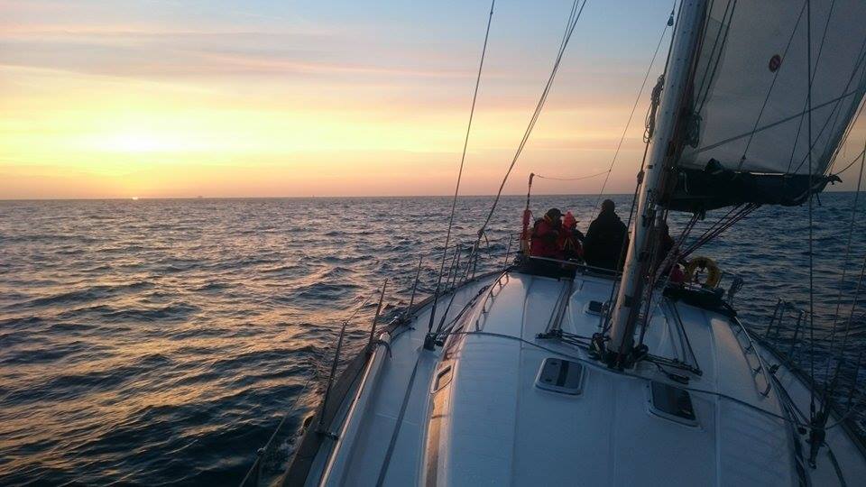 Powerboat Level 2 vs Advanced — sailboat navigating at sunset with several people aboard