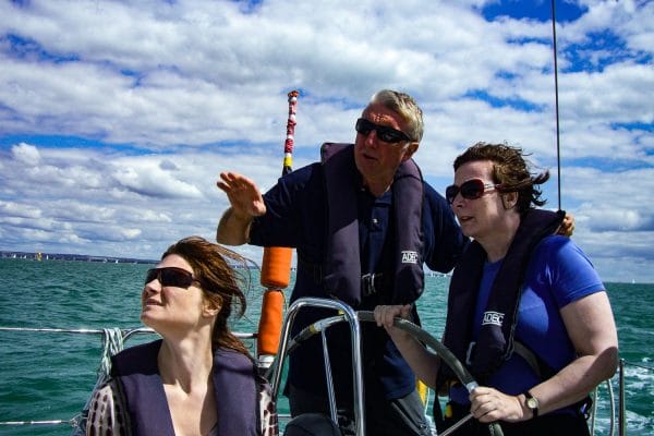 learning to sail at 40 — three people wearing life jackets on a boat gazing into distance