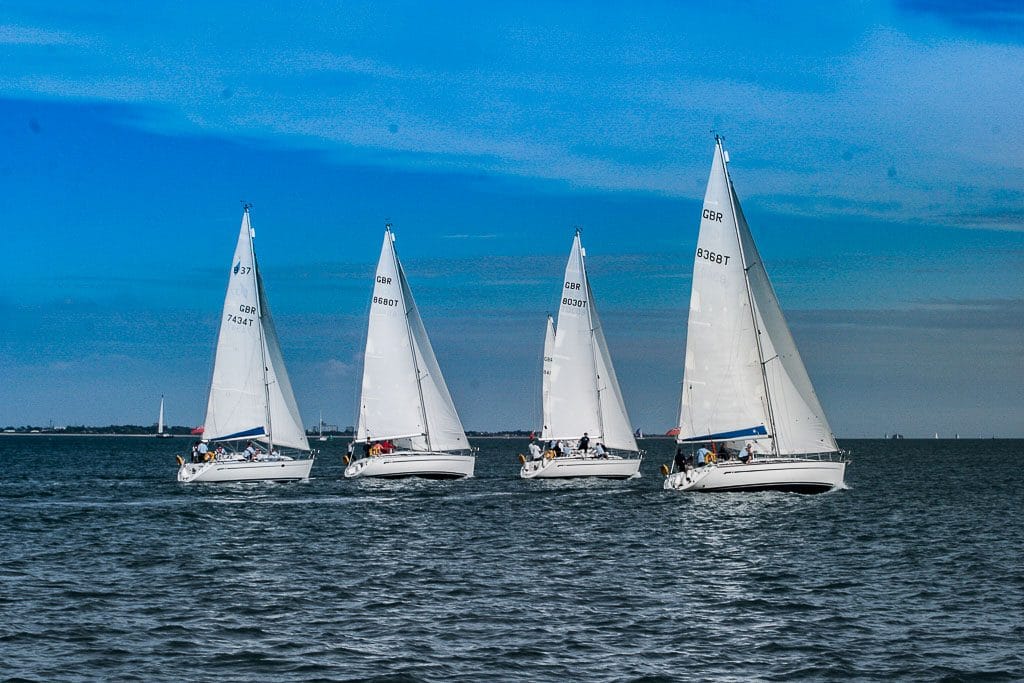RYA Day Skipper vs Yachtmaster — four sailboats racing on calm sea under a clear blue sky