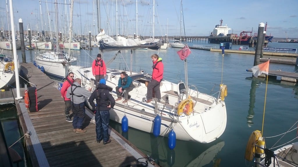 learning to sail at 40 — several people standing on a dock and boat in a marina
