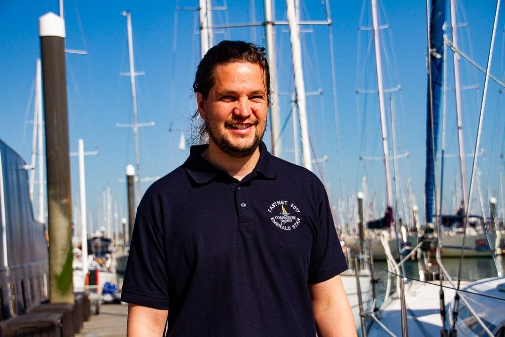 learning to sail at 40 — person standing on a sunny marina with sailboats in background