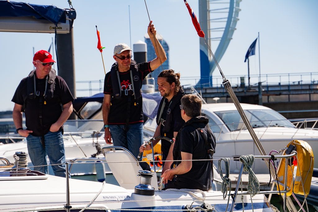 pass RYA practical exam first time — four people on a yacht having a conversation under sunny skies