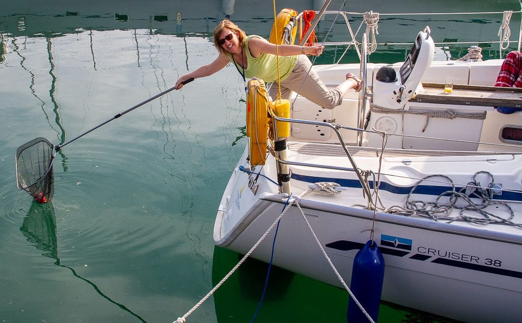 learning to sail at 40 — person on a boat leaning over using a net to reach something