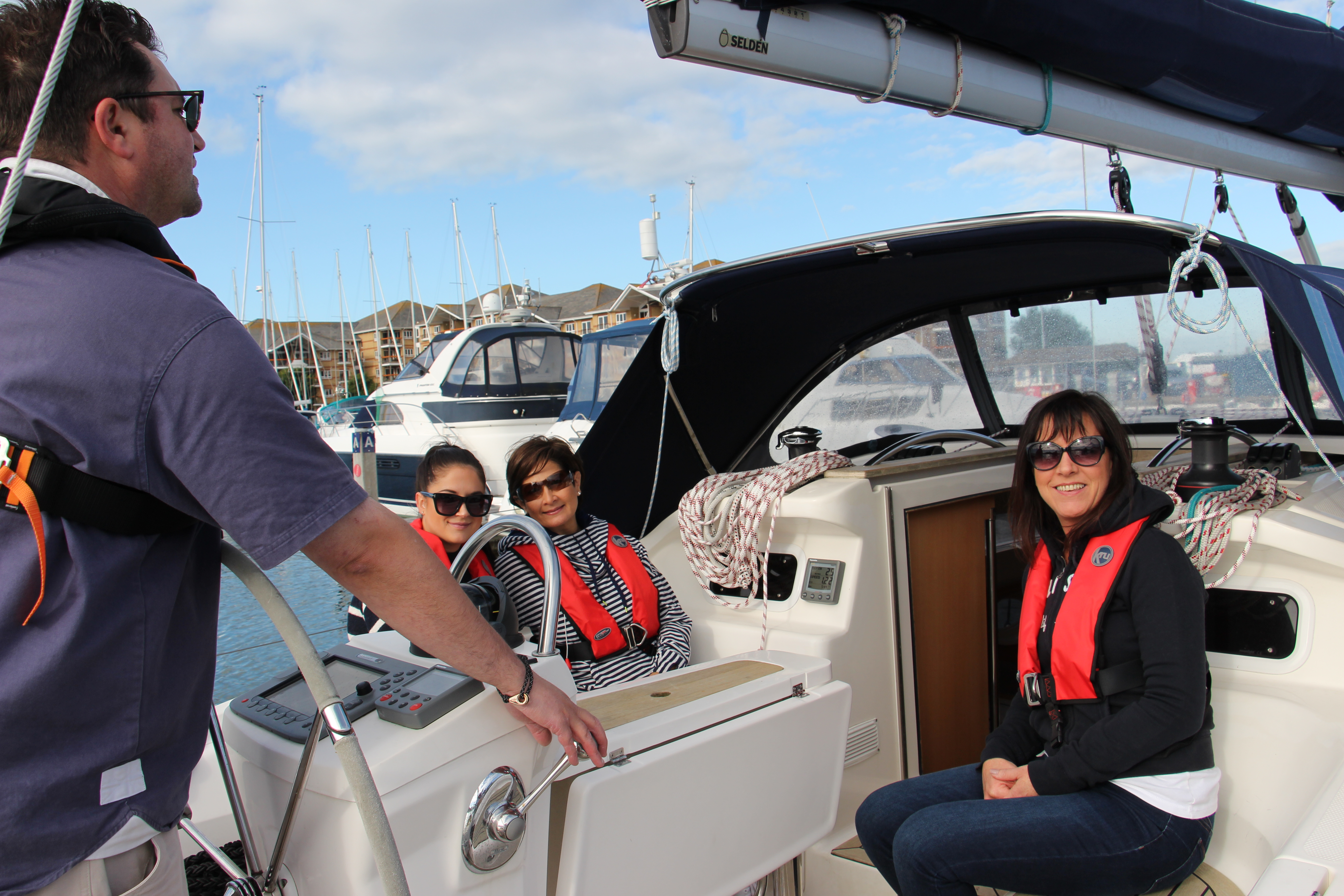 Sailing newsletter — four people enjoy sailing on a sunny day at a marina