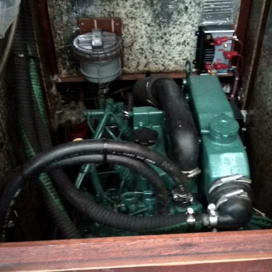 A compact engine with visible hoses and components is installed in a small, enclosed space, likely in a vehicle or machinery unit.