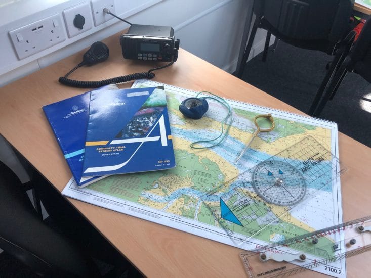 engine failure Solent — desk with navigational charts compass rulers and communication tools