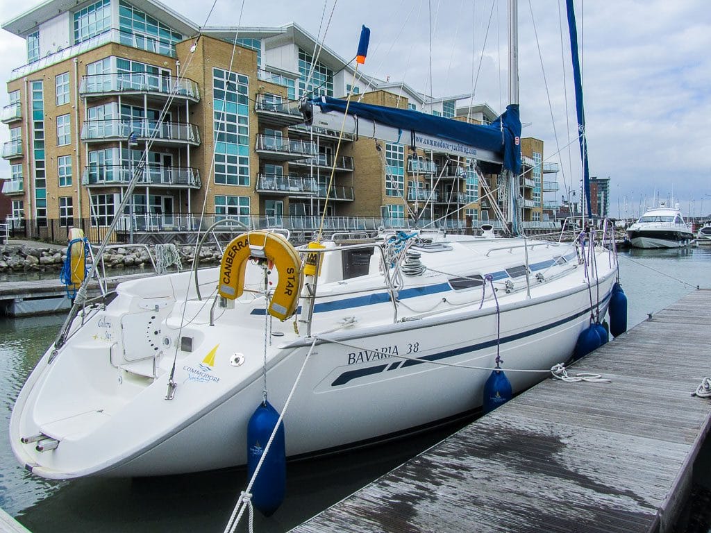online vs classroom RYA theory — sailboat docked in marina beside modern apartment buildings