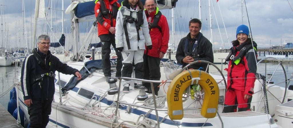 learning to sail at 40 — six people in nautical gear standing on a docked sailboat