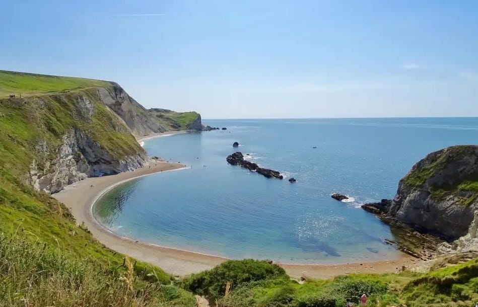 solo sailing UK legal requirements — picturesque bay with curved beach surrounded by cliffs
