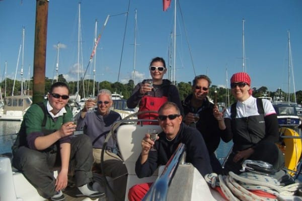 Powerboat Level 2 vs Advanced — six people on a sailboat toasting with drinks surrounded by water