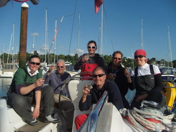 Powerboat Level 2 vs Advanced — six people relaxing on a docked sailboat holding drinks