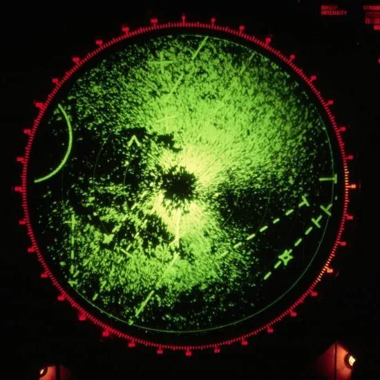A green radar screen displays various signals, lines, and points on a dark background, suggesting detection or surveillance activity within a circular grid.